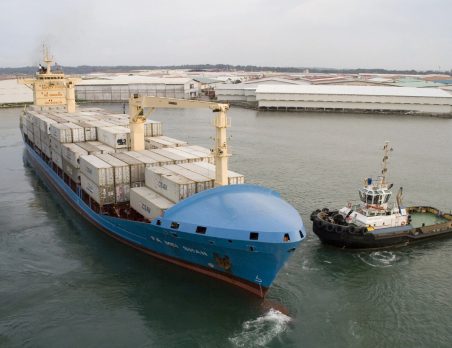 A large blue boat with two smaller boats in it.